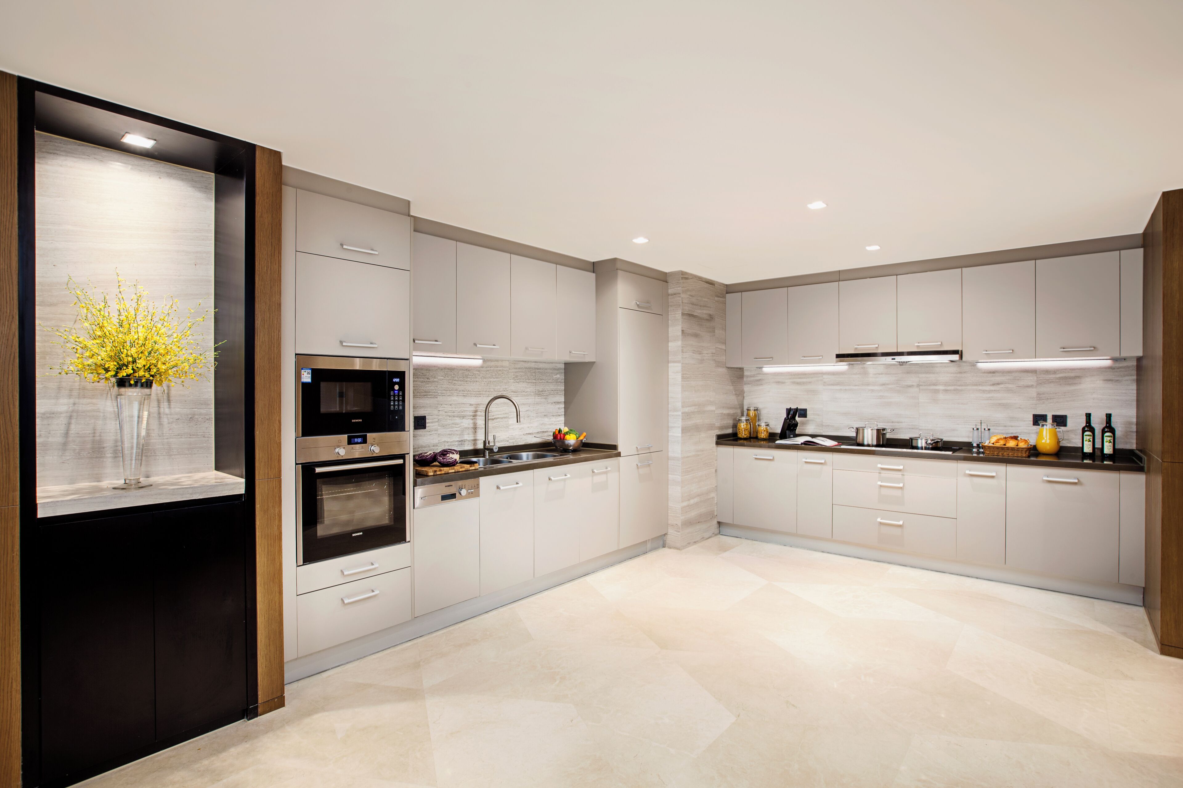 A modern kitchen with stainless steel appliances, white cabinetry, and a marble backsplash.