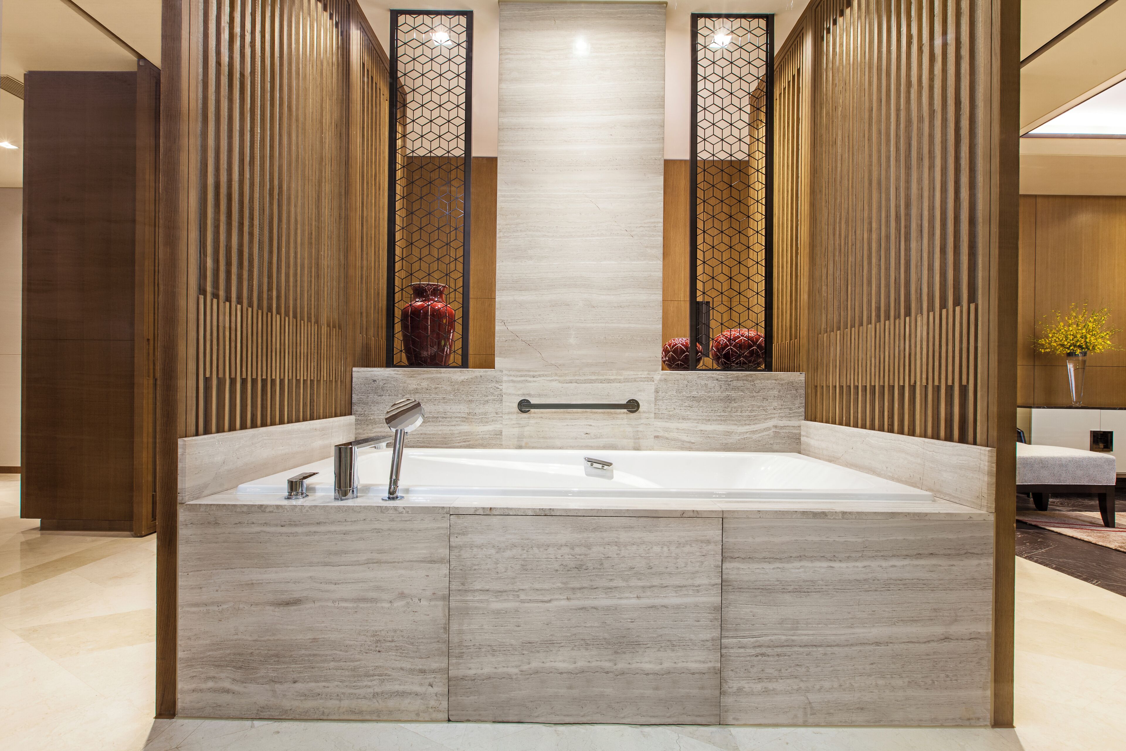 Ein modernes Badezimmer mit einer großzügigen Badewanne, Holzvertäfelung und einem zentral platzierten Spiegel.