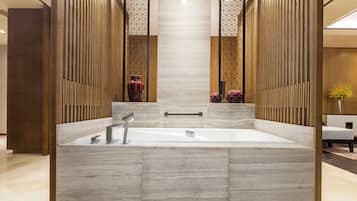 Ein modernes Badezimmer mit einer großzügigen Badewanne, Holzvertäfelung und einem zentral platzierten Spiegel.
