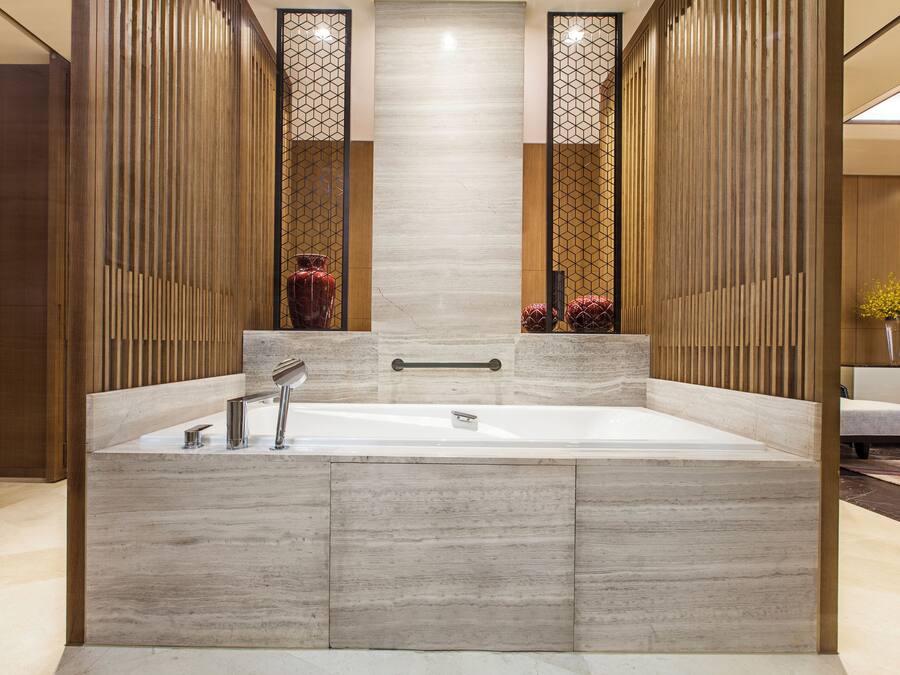 Un baño moderno con una bañera grande, paneles de madera y un espejo central.