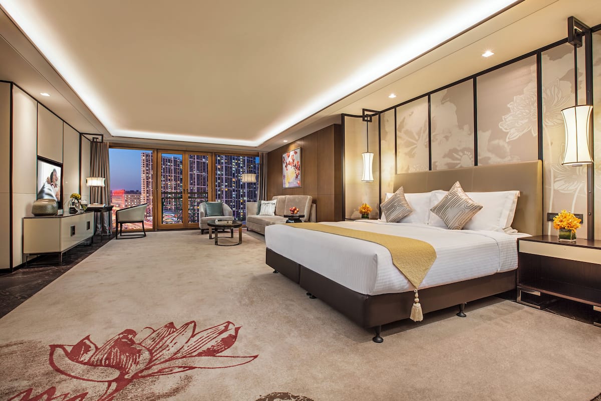 Una habitación de hotel moderna con una cama grande, un escritorio, una silla y vistas a la ciudad.