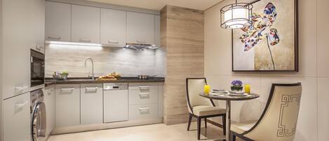 A modern kitchen with grey cabinets, a built-in oven, and a dining area with a round table and two chairs.