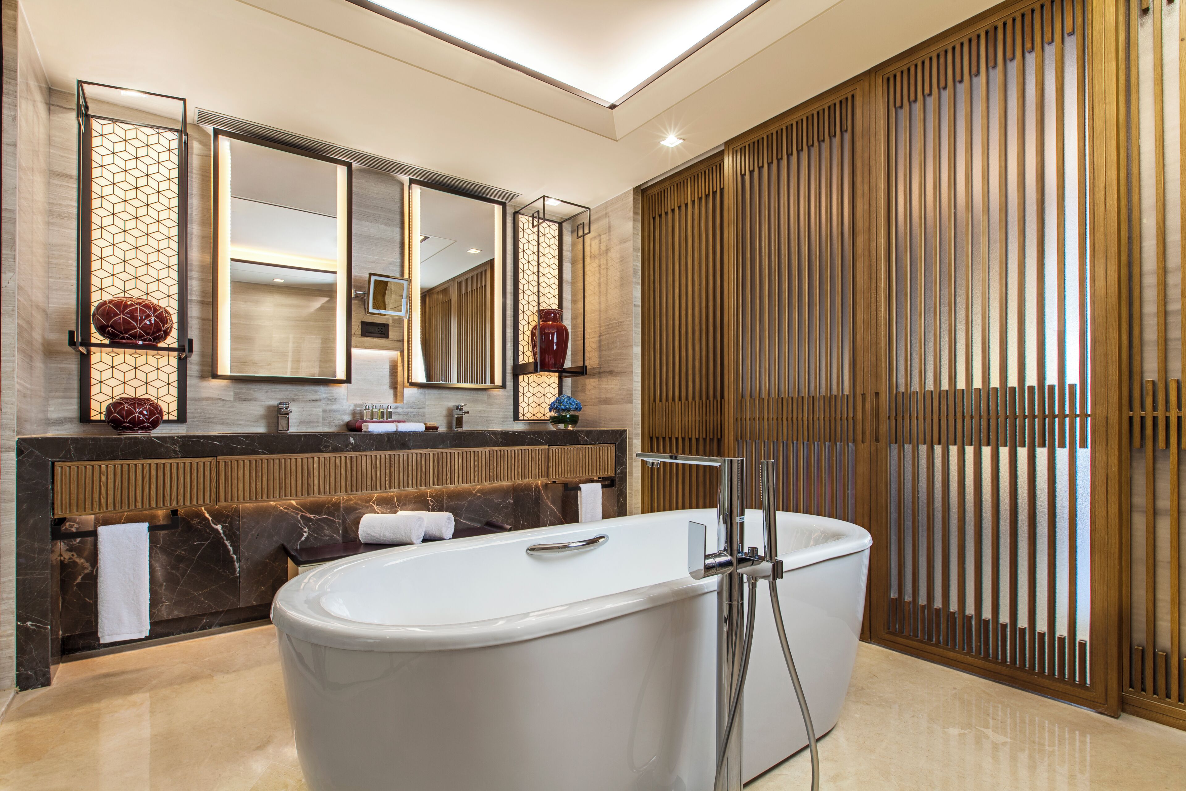 A modern bathroom with a large bathtub, a vanity with a mirror, and a decorative wall panel.