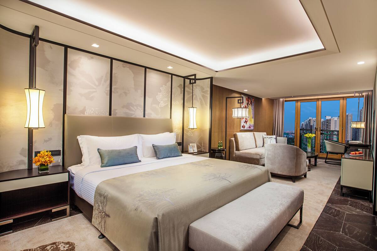 Una habitación de hotel moderna con una cama grande, una zona de estar y vistas a la ciudad.
