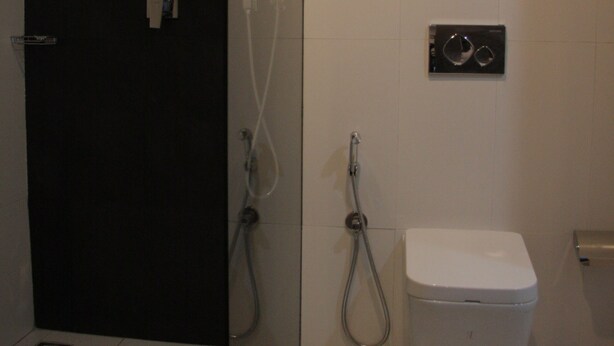 A modern bathroom with a glass shower enclosure, a white toilet, and a wall-mounted faucet. - Days Inn & Suites by Wyndham Bengaluru Whitefield (Bengaluru)
