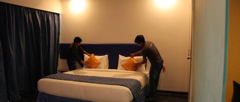 Una habitación de hotel con una cama grande, un ventilador de techo y una puerta a la derecha.