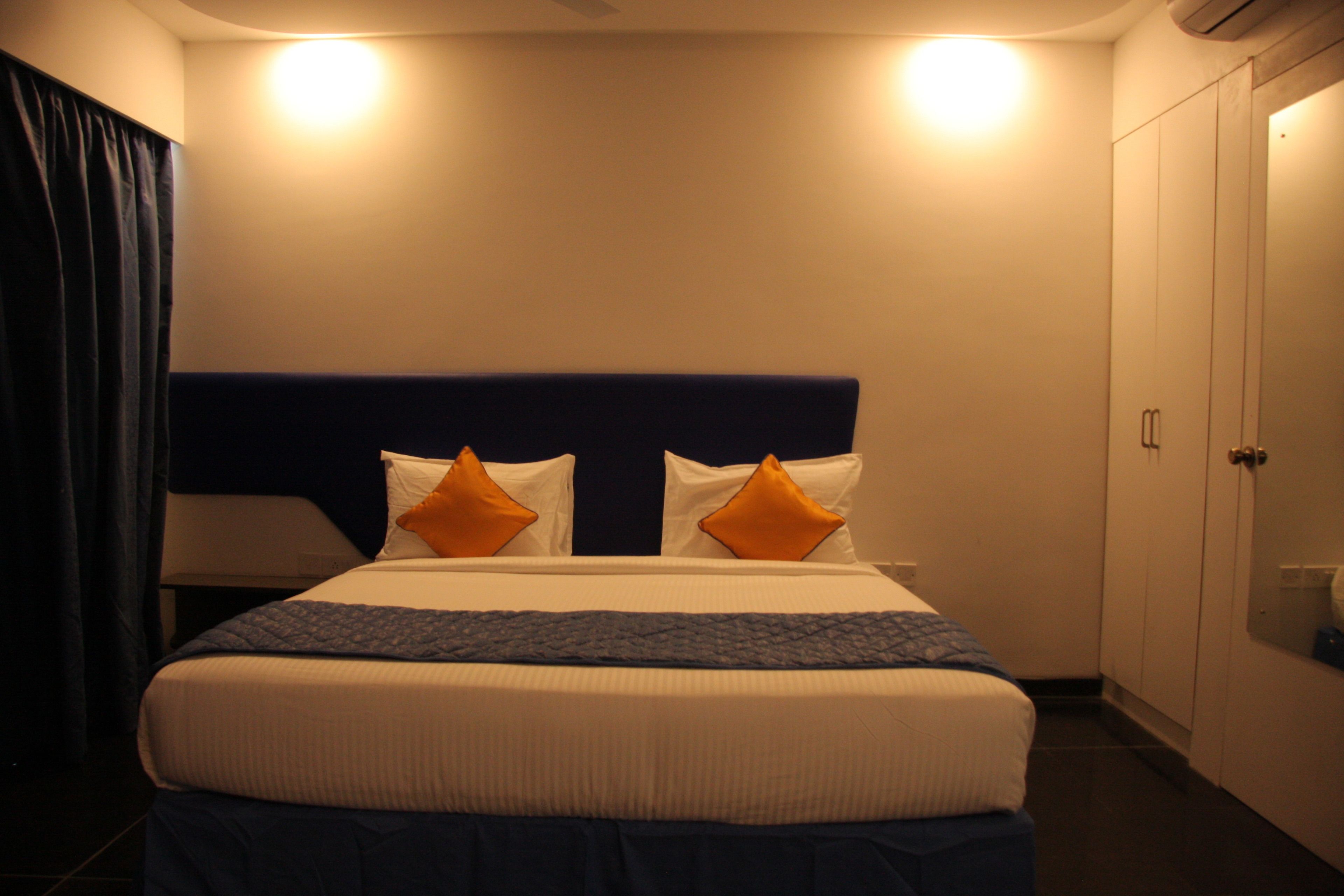 Ein Hotelzimmer mit Bett, Nachttisch, Lampe und Kleiderschrank.