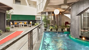 Una piscina interior con alfombra roja, bancos blancos y plantas en macetas.