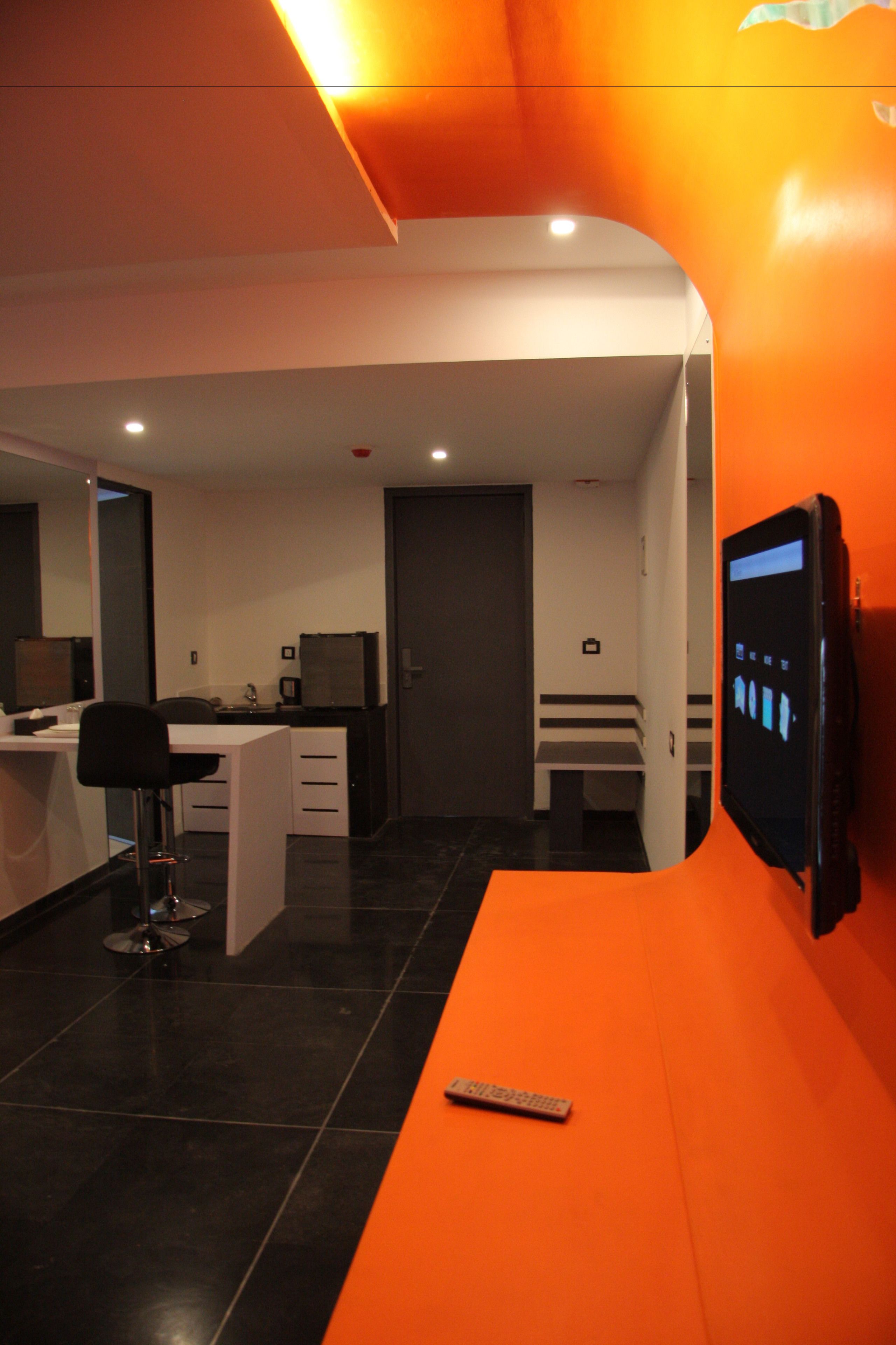 A modern hotel room with a desk, chair, and a television mounted on the wall.
