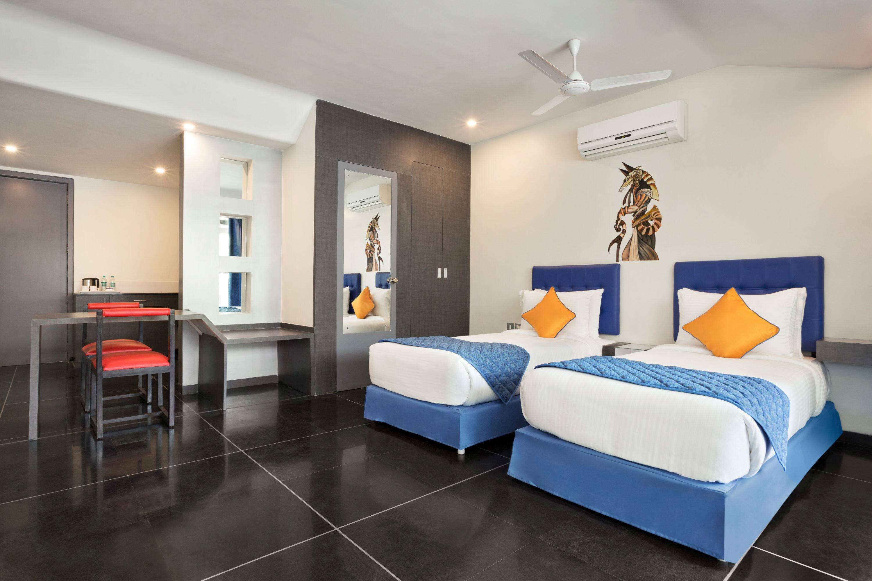 A modern hotel room with two beds, a desk, and a chair.