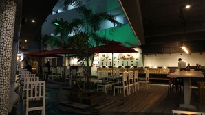 Un comedor interior con mesas y sillas, una piscina y una cocina al fondo.