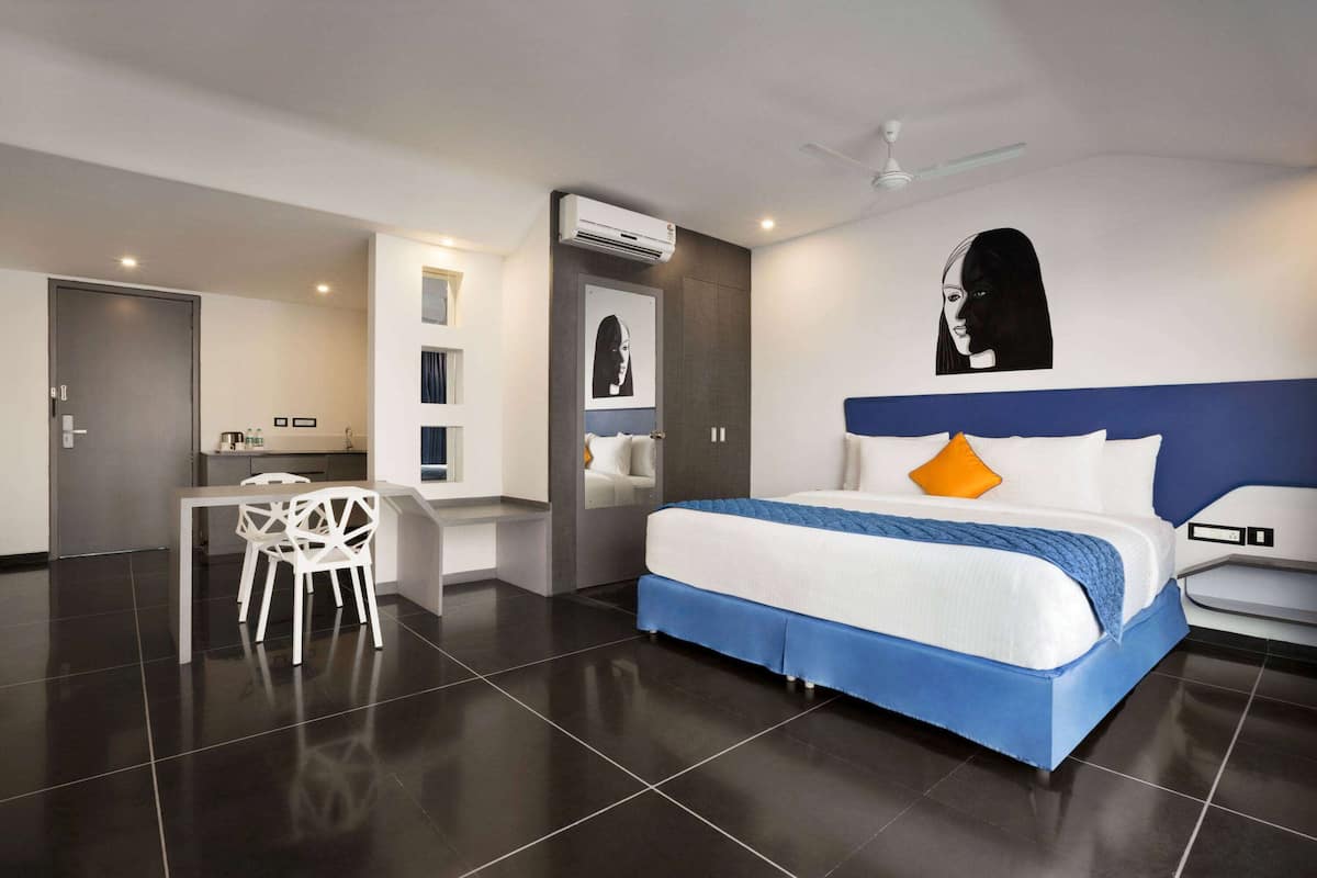 A modern hotel room with a large bed, a desk, and a chair.