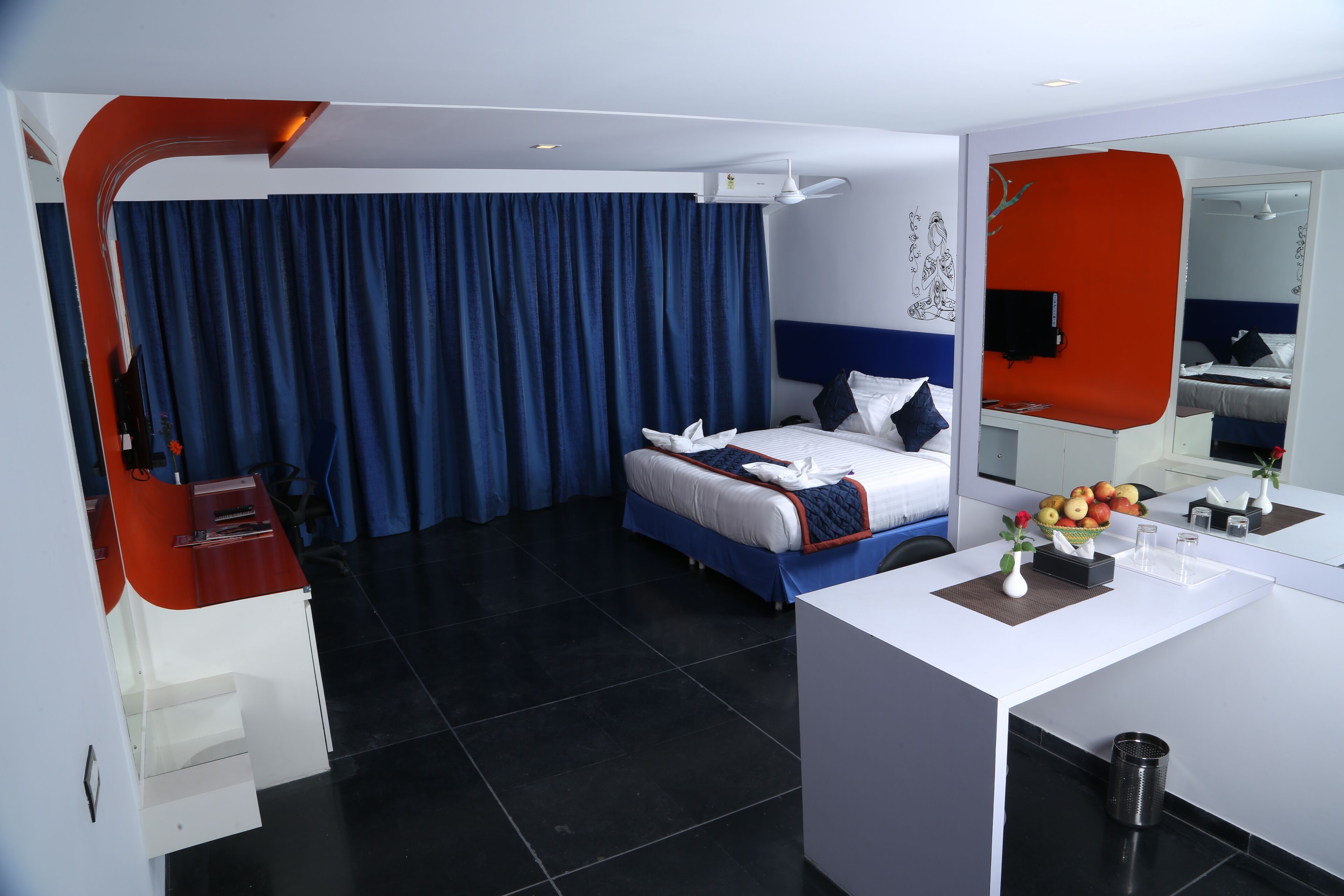 A modern hotel room with a bed, a desk, a mirror, and a large window with curtains.