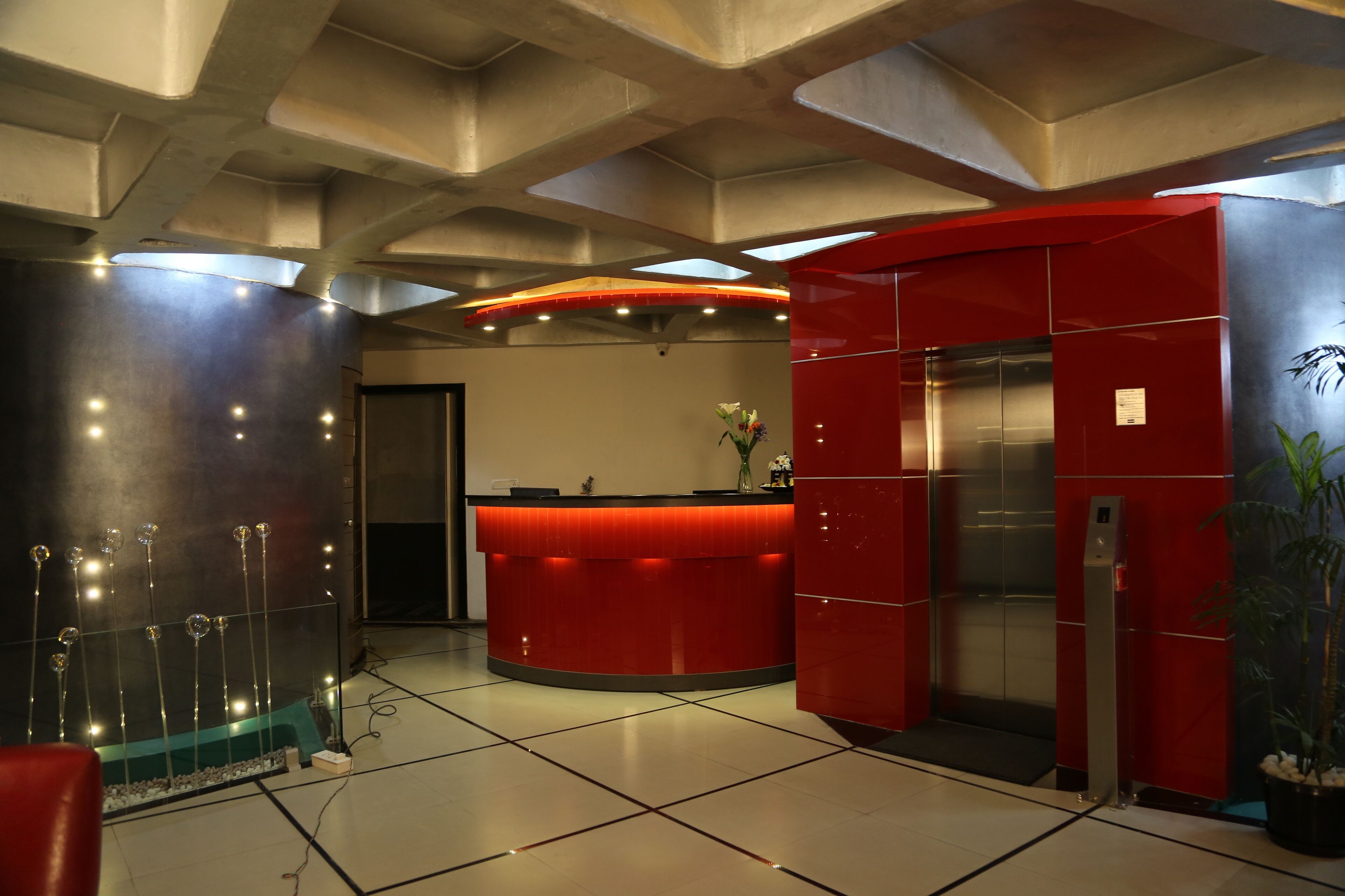 A modern reception area with a red counter, a glass display case, and an elevator.