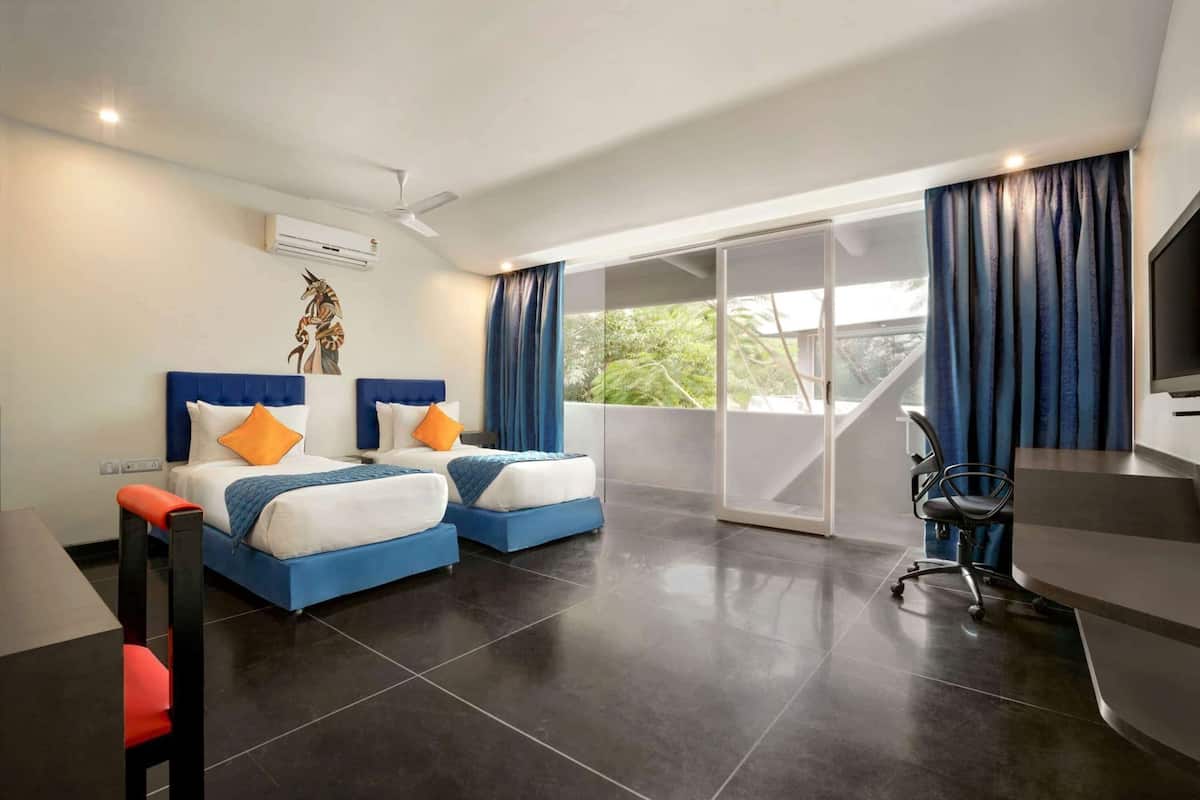 A modern hotel room with two beds, a desk, a chair, and a TV.