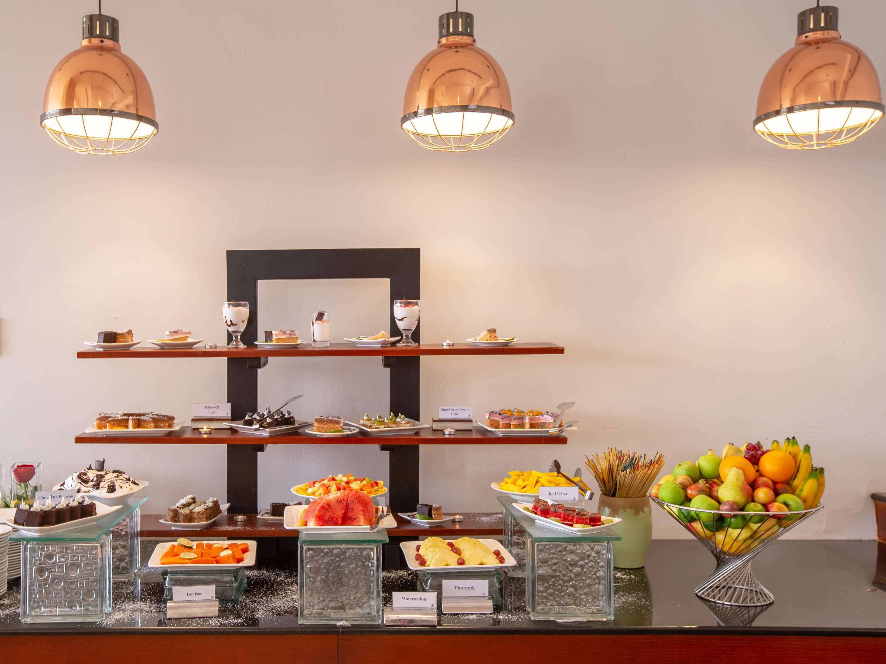 A buffet setup with various food items and a fruit bowl.