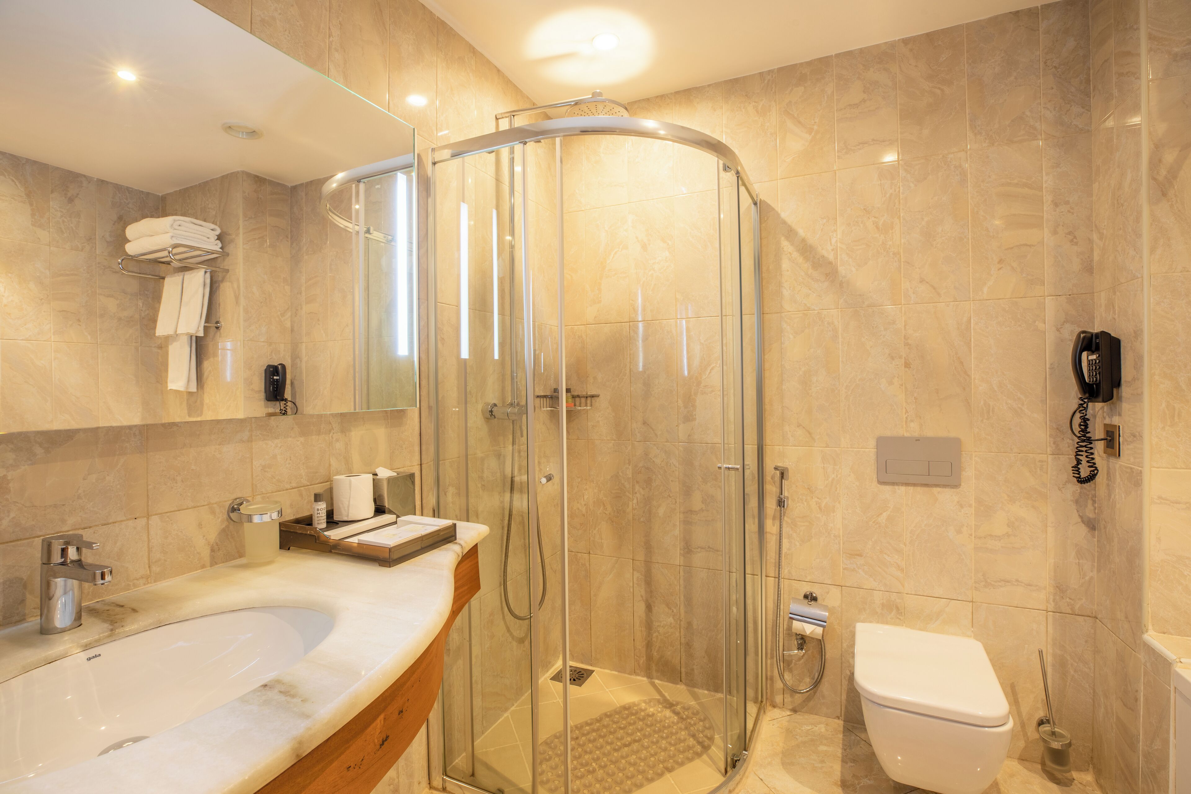 Ein modernes Badezimmer mit einer gläsernen Duschkabine, einer freistehenden Toilette und einer großen Badewanne.