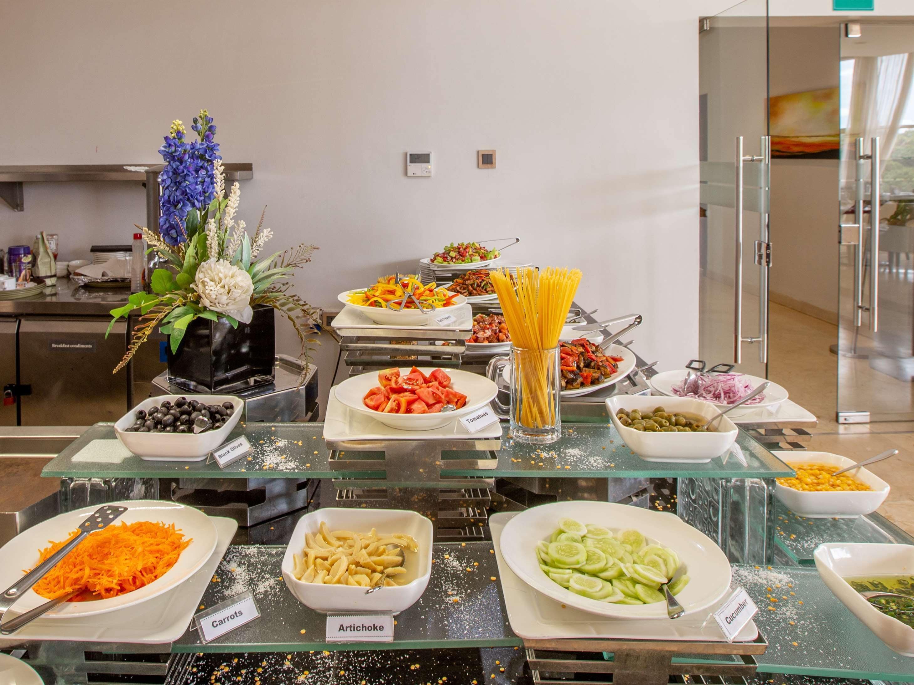 A buffet with various dishes including artichoke, carrots, and cucumber.