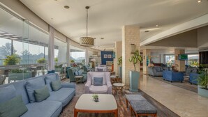 Un vestíbulo amplio con techo alto, muebles modernos y ventanas grandes que ofrecen vistas al exterior.