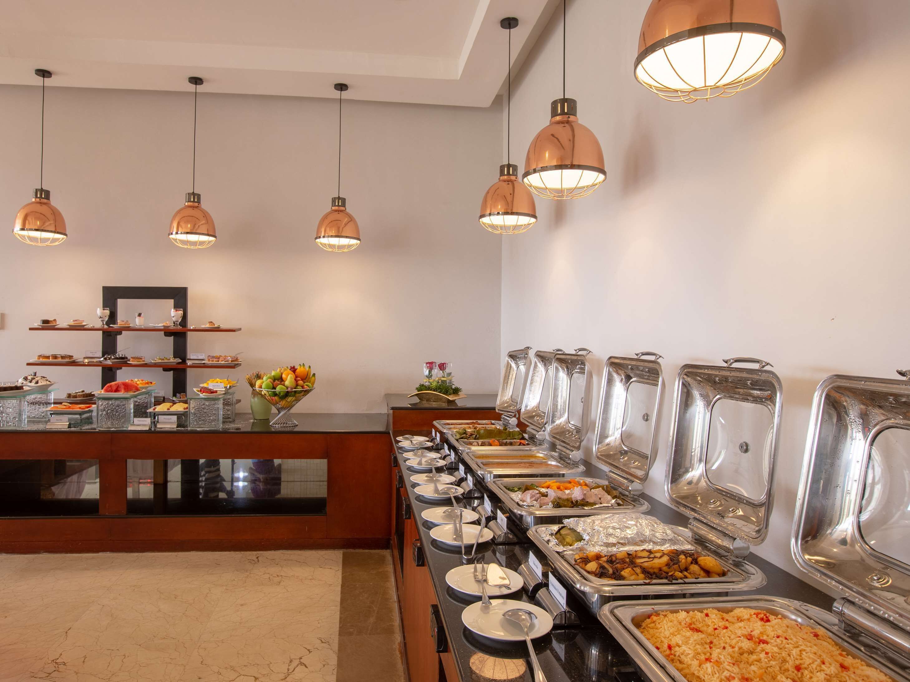 A buffet setup with various food stations and overhead lighting.