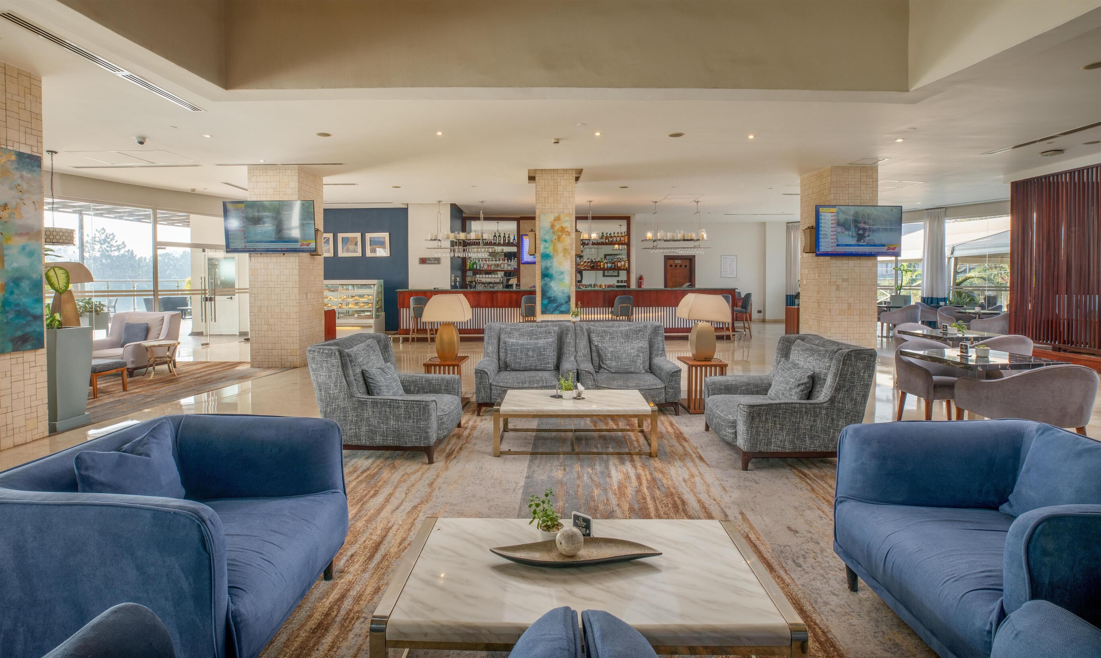 A spacious lobby with a bar area, seating arrangements, and a large artwork on the wall.