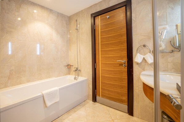 Un baño moderno con bañera, una puerta de madera y cabina de ducha de vidrio.