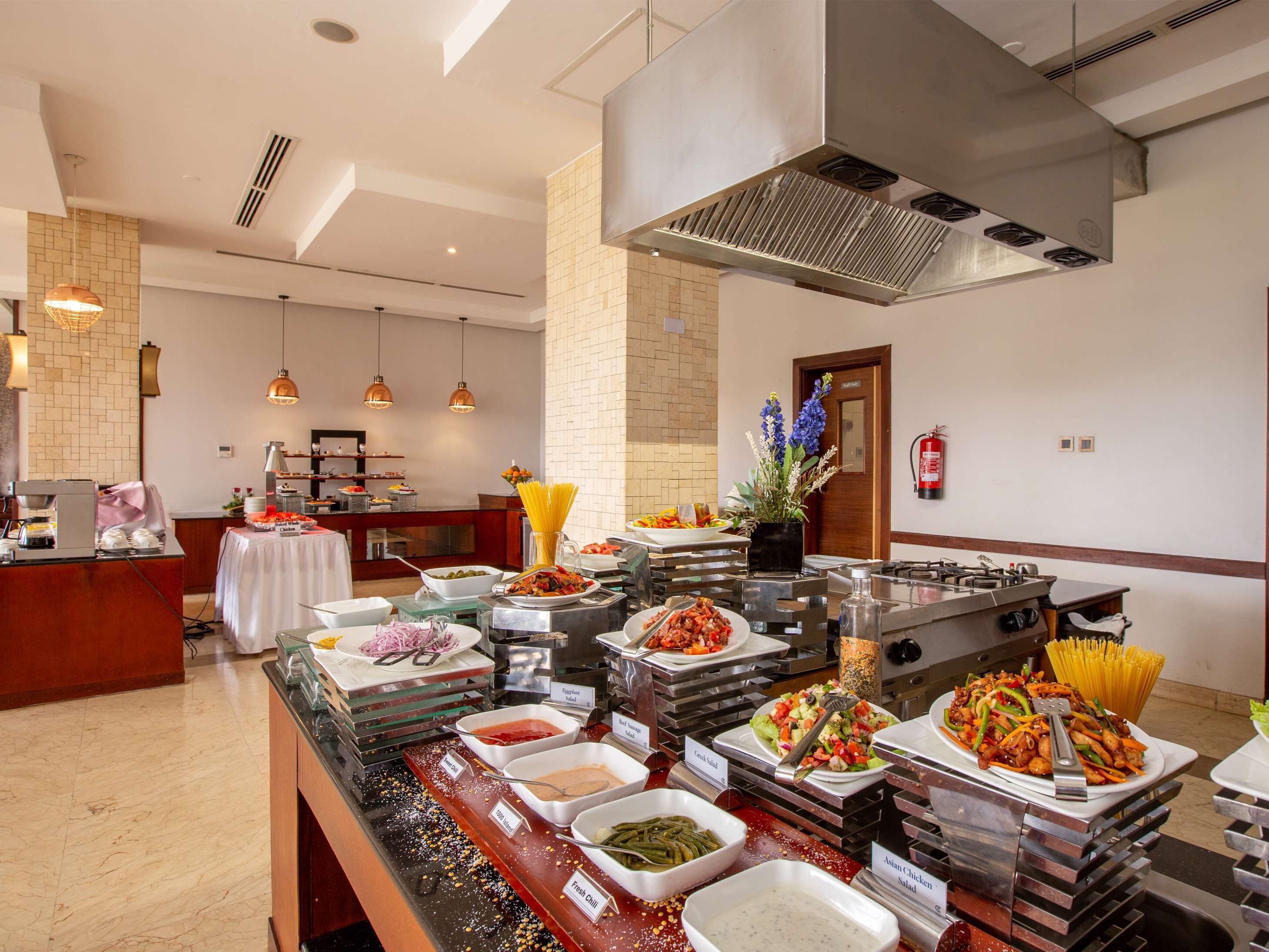 A buffet with various dishes and a kitchen area in the background.