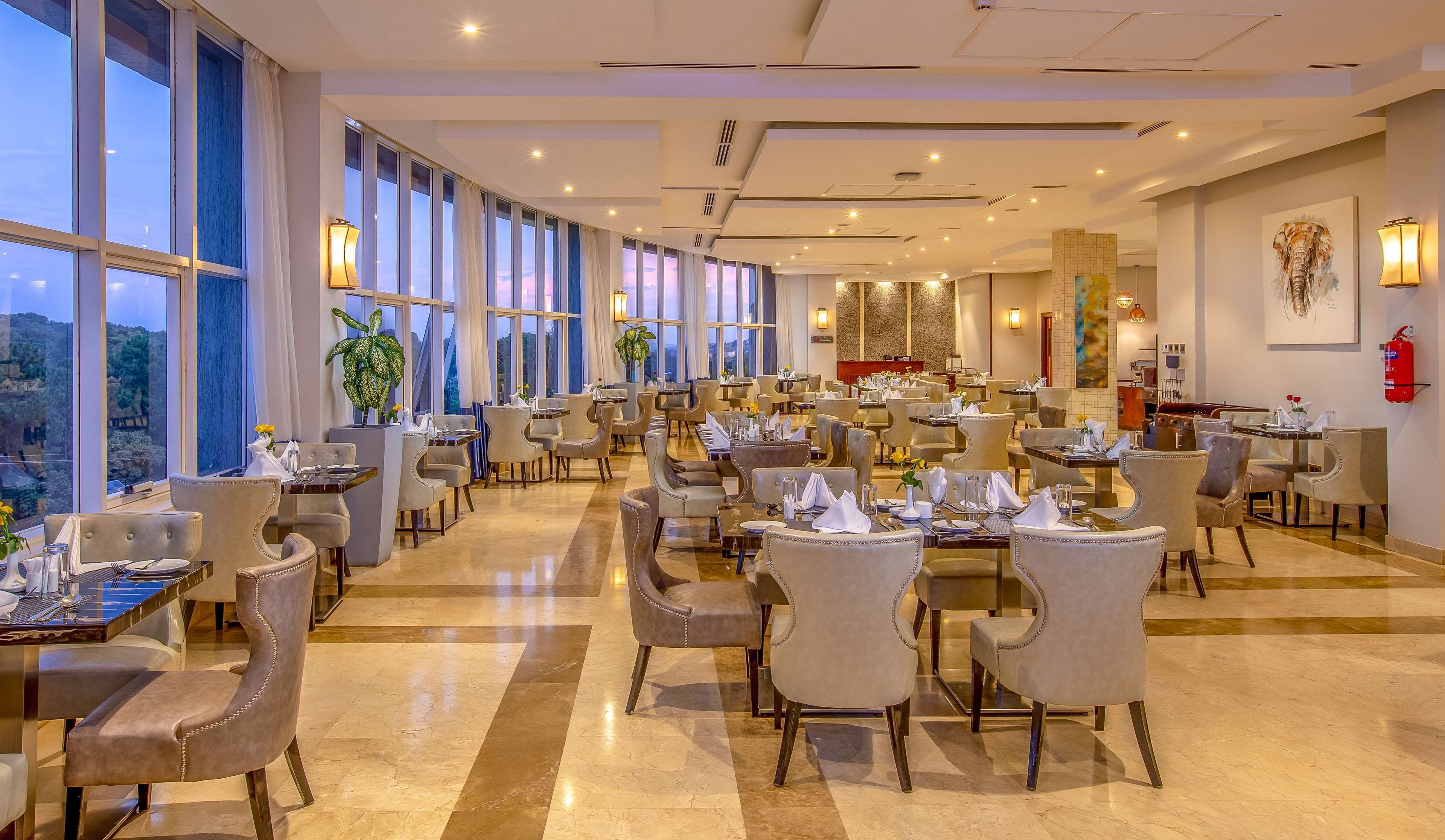 Un restaurante espacioso con techos altos, ventanas amplias y diversas opciones de asientos.