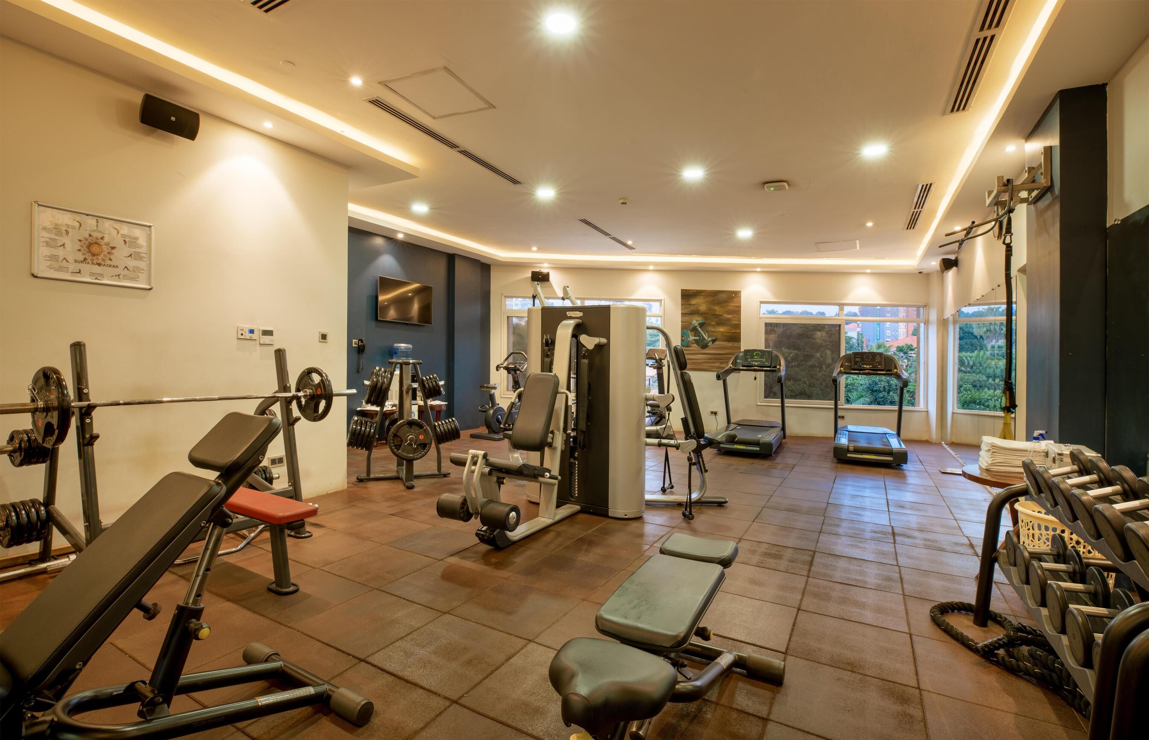 Un gimnasio bien equipado con diversas máquinas de ejercicio, estantes para pesas y bancos.