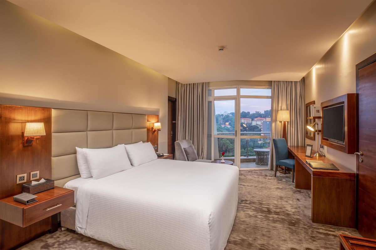 Een hotelkamer met een groot bed, een bureau, een stoel en een televisie.