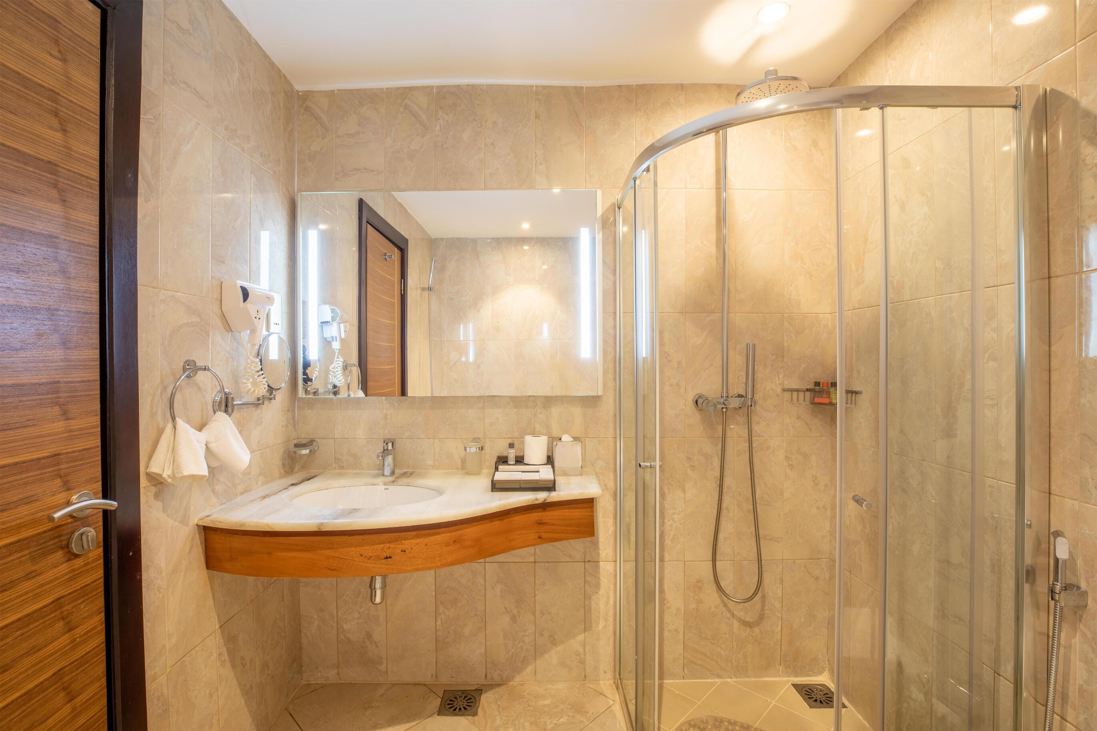 Un baño moderno con cabina de ducha curva, tocador de madera y un espejo grande.