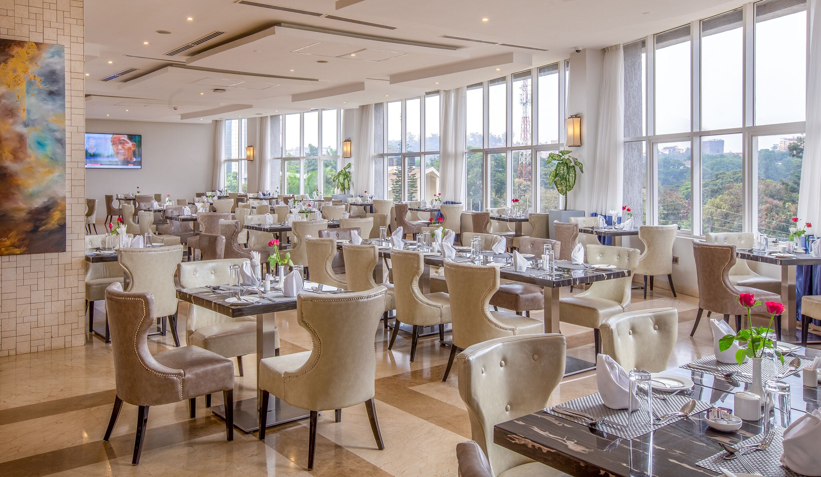 Un restaurante espacioso con múltiples mesas y sillas, amplias ventanas que ofrecen vistas al exterior y un diseño interior moderno.