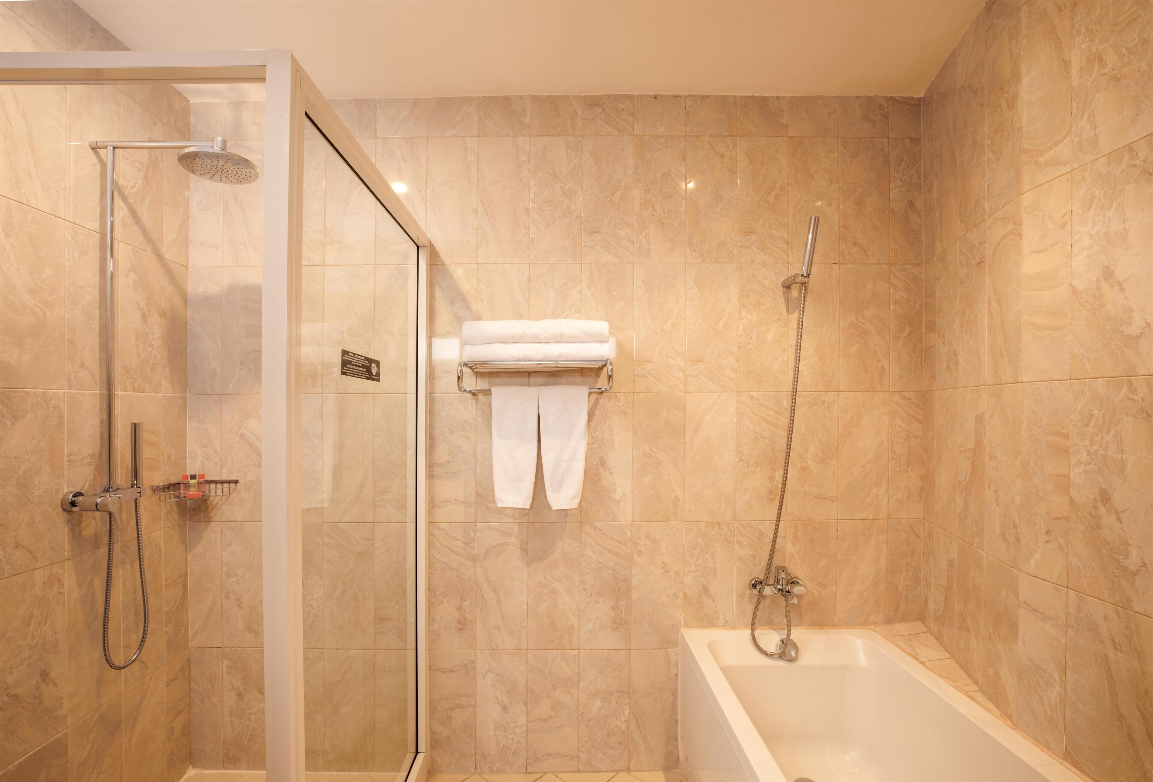 Une salle de bain moderne avec une douche à parois de verre, une baignoire et un porte-serviettes avec des serviettes pliées.