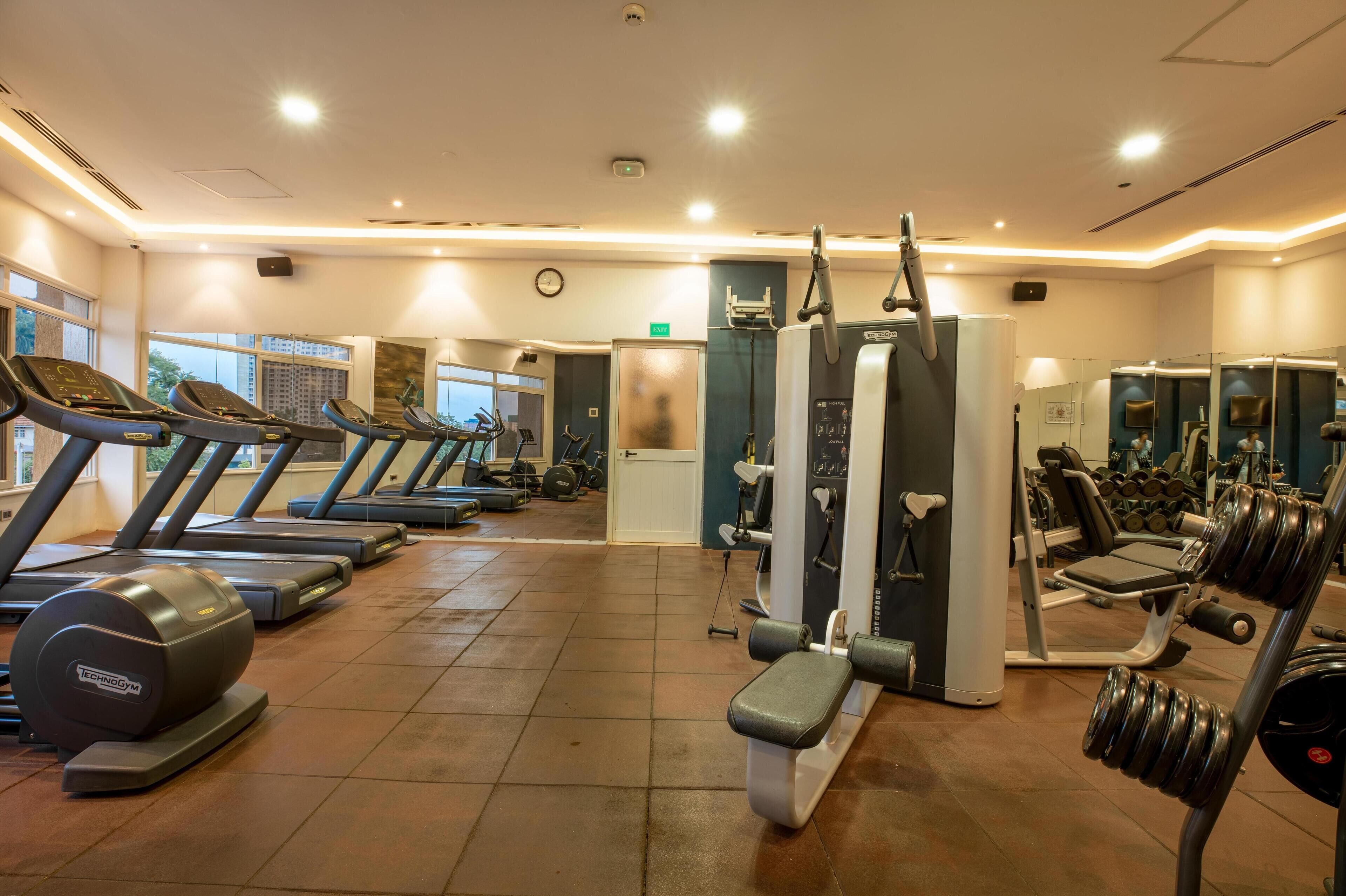 A gym with treadmills, weight machines, and dumbbells.