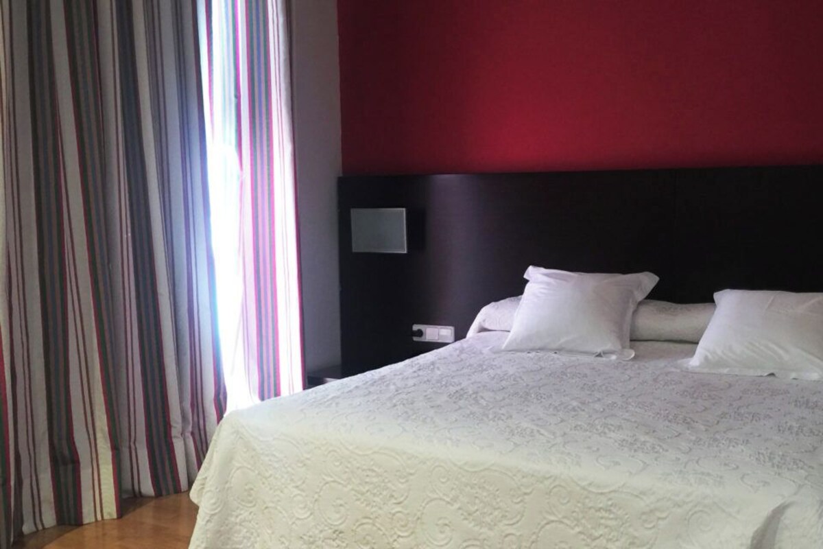A hotel room with a large bed, a dark headboard, and a striped curtain.