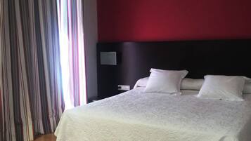 A hotel room with a large bed, a dark headboard, and a striped curtain.