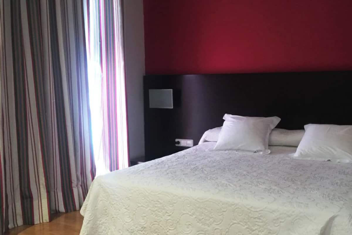 A hotel room with a large bed, a dark headboard, and a striped curtain.