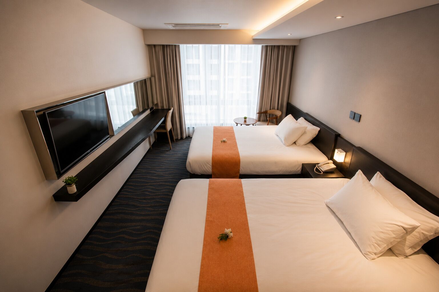 A hotel room with two beds, a TV, a desk, and a chair.