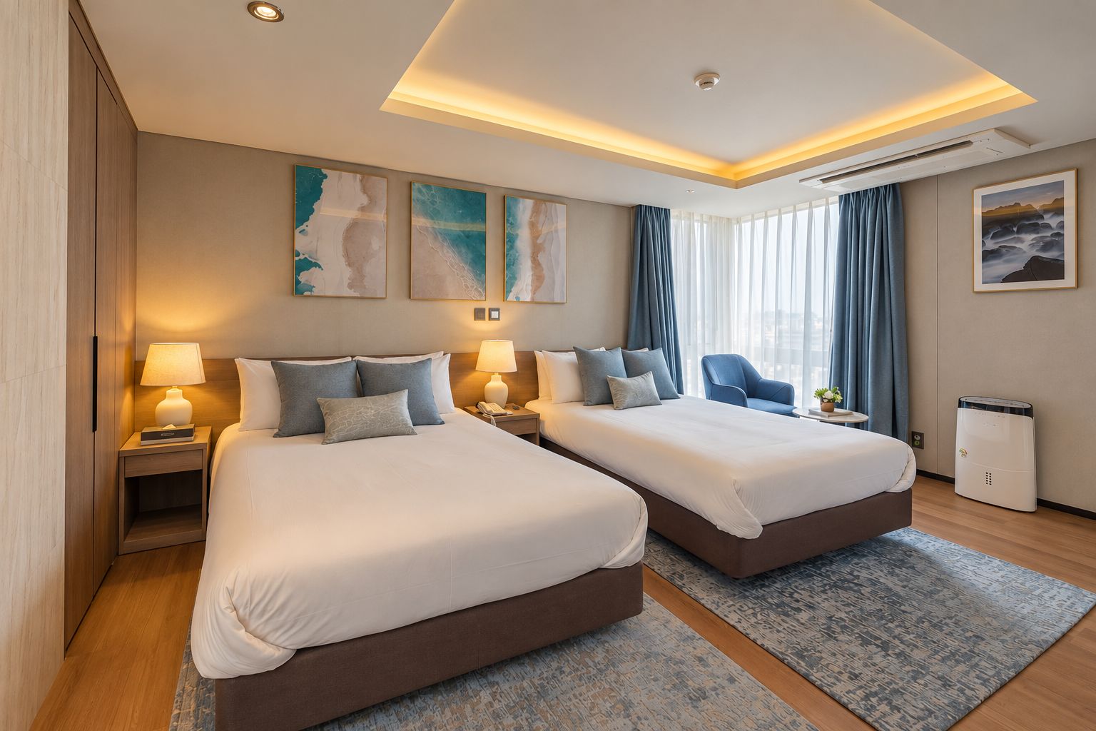 A hotel room with two beds, a desk, a chair, a small table with a plant, and artwork on the walls.