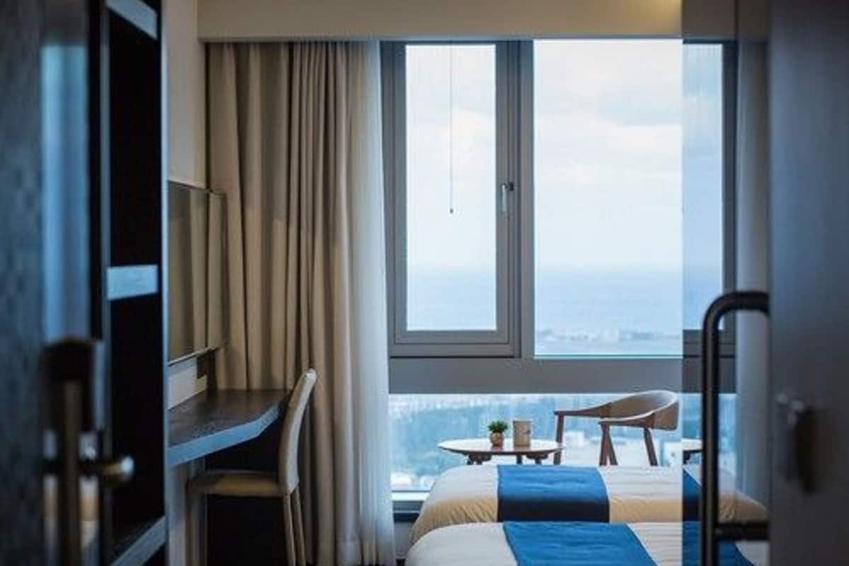Una habitación de hotel con cama, escritorio y vistas de la ciudad.