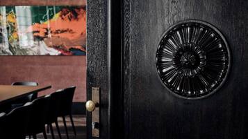 A dark wooden door with a brass doorknob and a decorative circular metal plate.