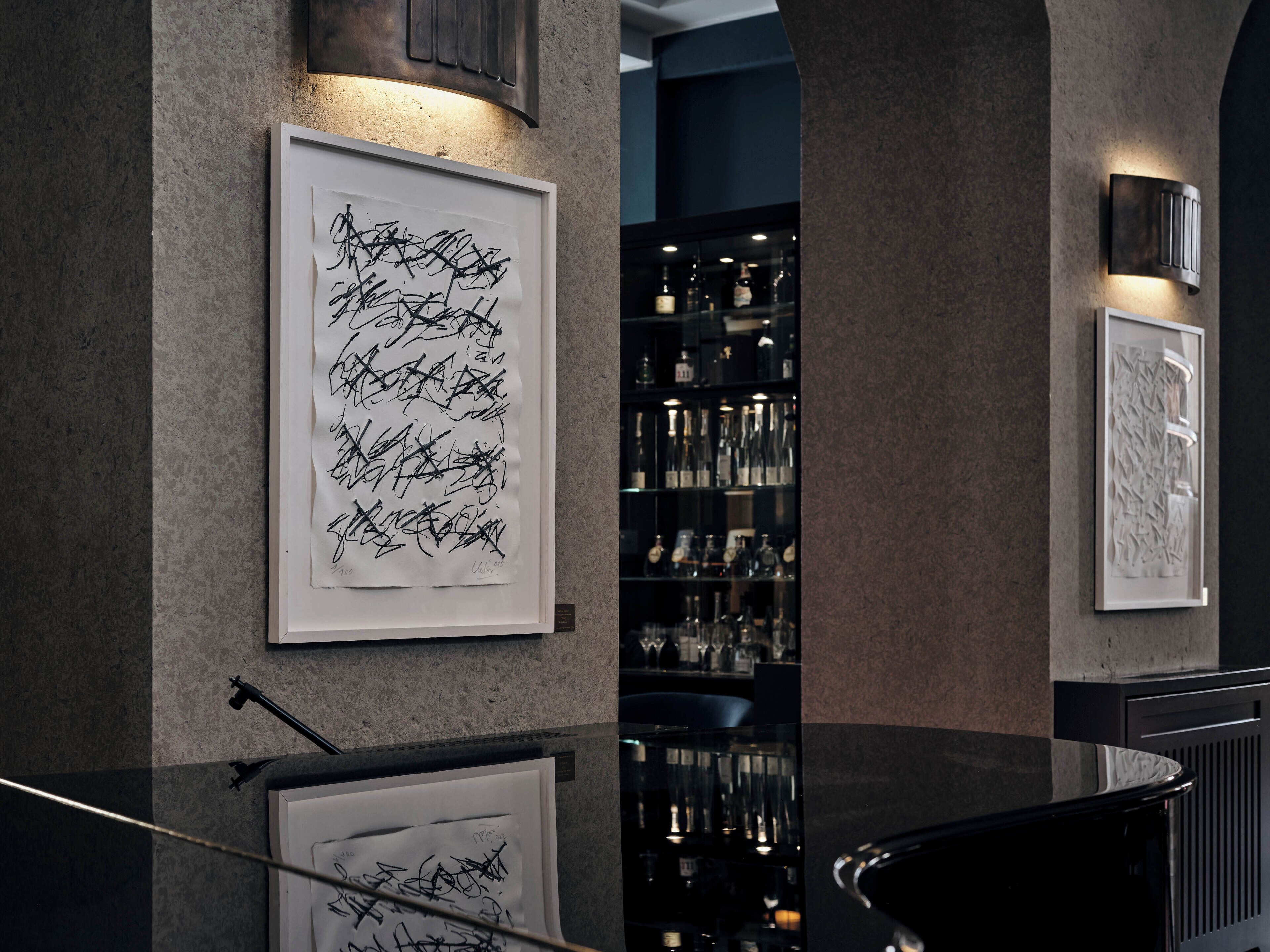Um interior moderno com arte abstrata nas paredes, área de bar com prateleiras cheias de garrafas e um balcão preto elegante.