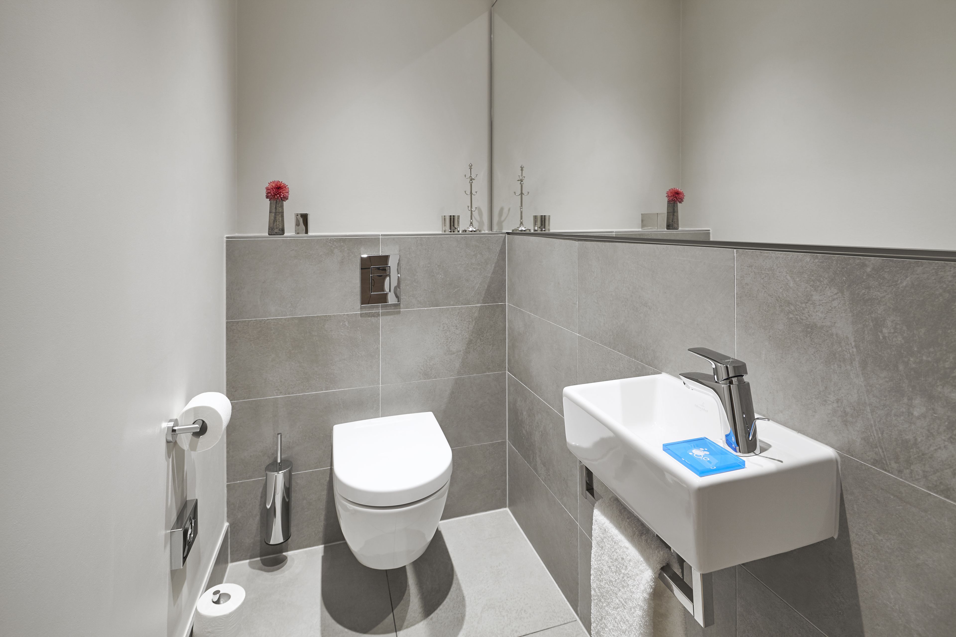 A modern bathroom with a toilet, sink, and towel rack.