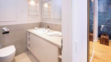 Un baño moderno con lavamanos, espejo y retrete blancos.