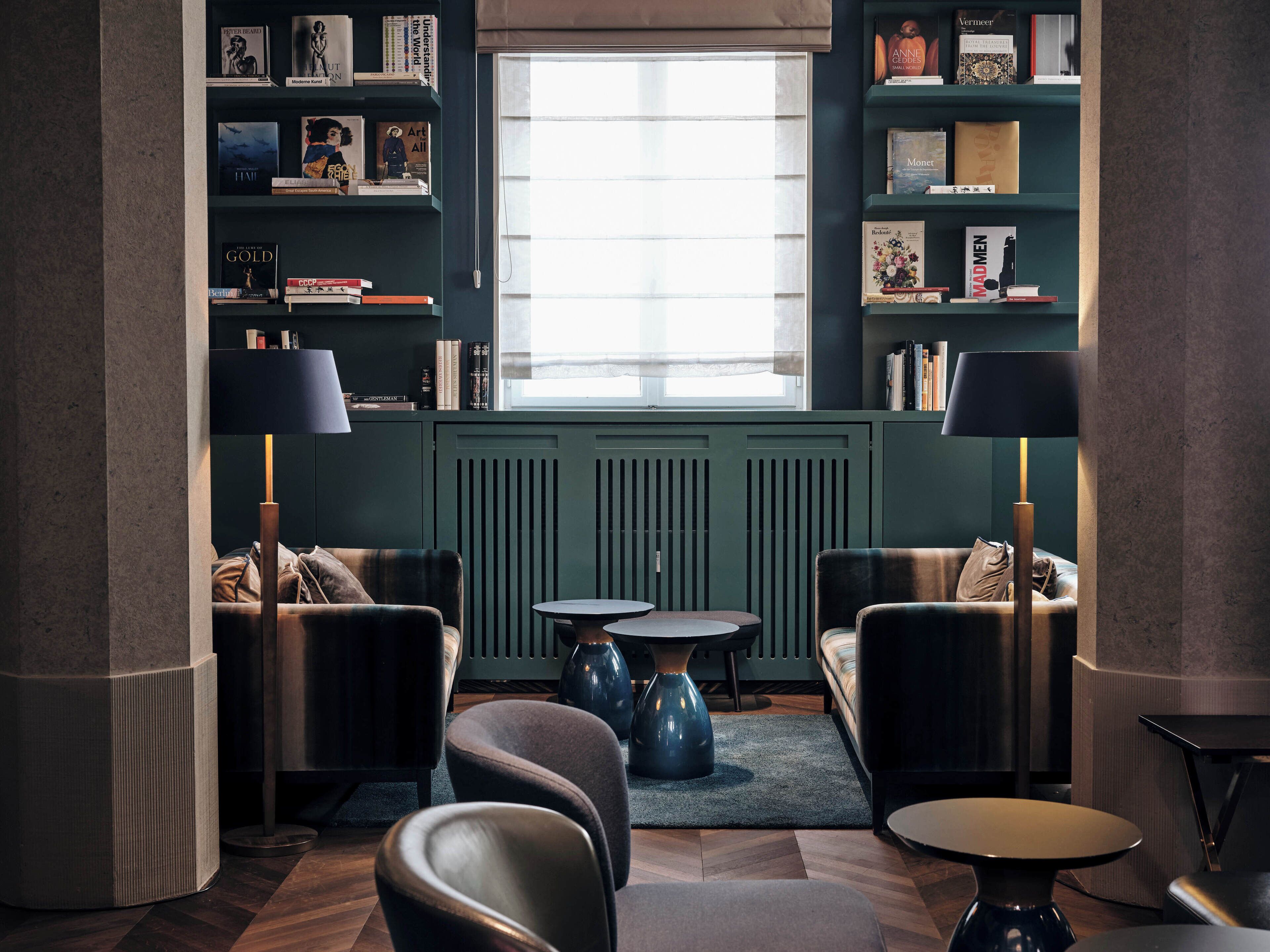 Un rincón acogedor para leer con dos sillones, una mesita de centro y una estantería llena de libros.