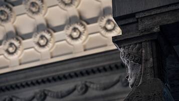 Primer plano de una columna arquitectónica clásica con intrincados grabados, parte de una estructura más grande con techo decorado.