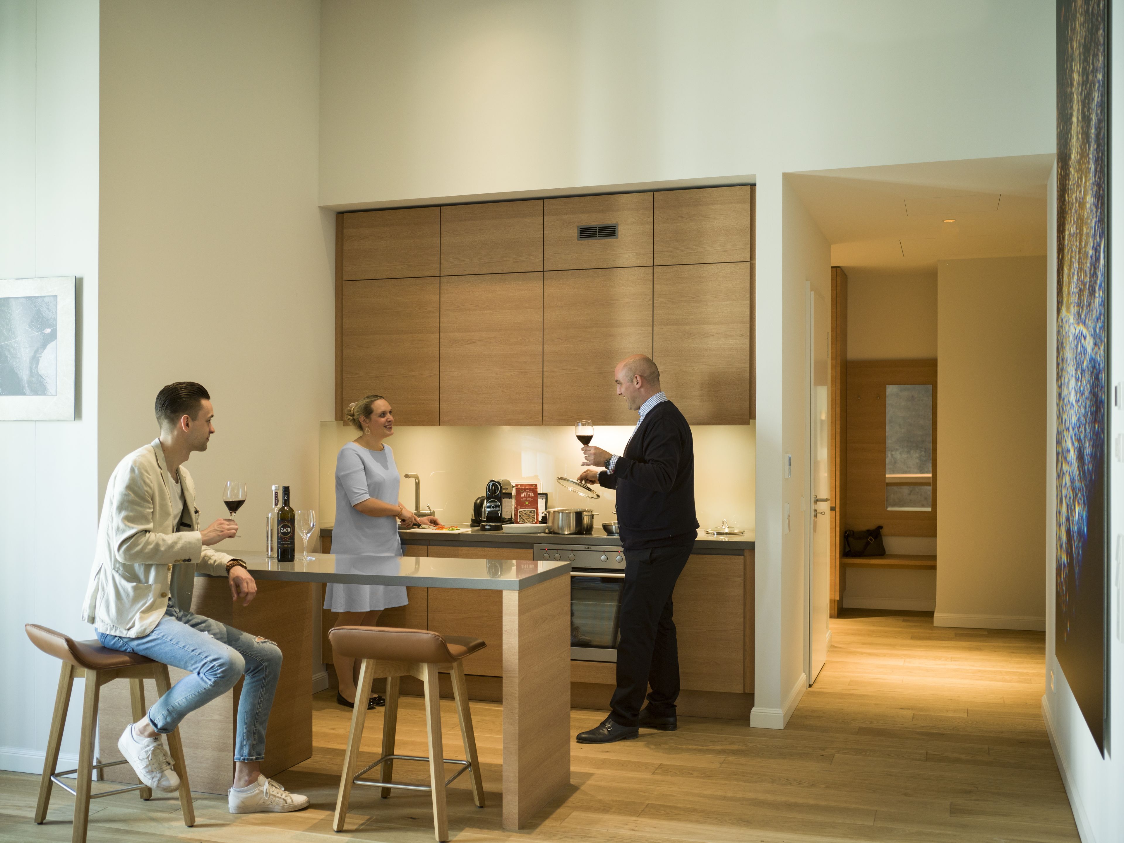 A modern kitchen with wooden cabinets, a central island, and a dining area with stools.