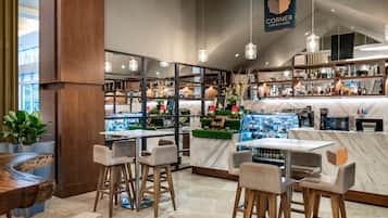 Un interior de cafetería moderna con taburetes, una barra de mármol y diversas exhibiciones de café y té.