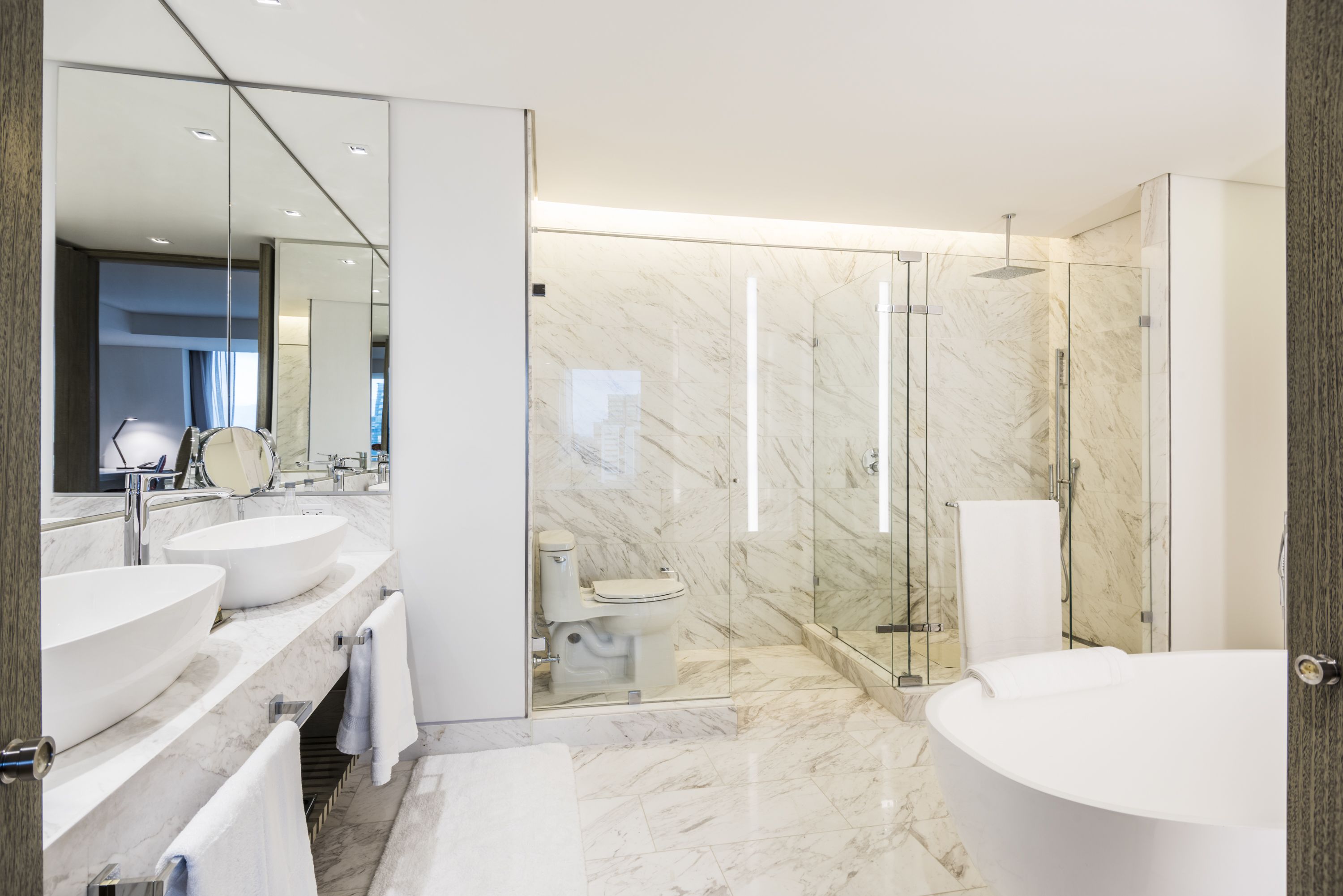 A modern bathroom with a freestanding bathtub, a glass-enclosed shower, and a vanity with two sinks.