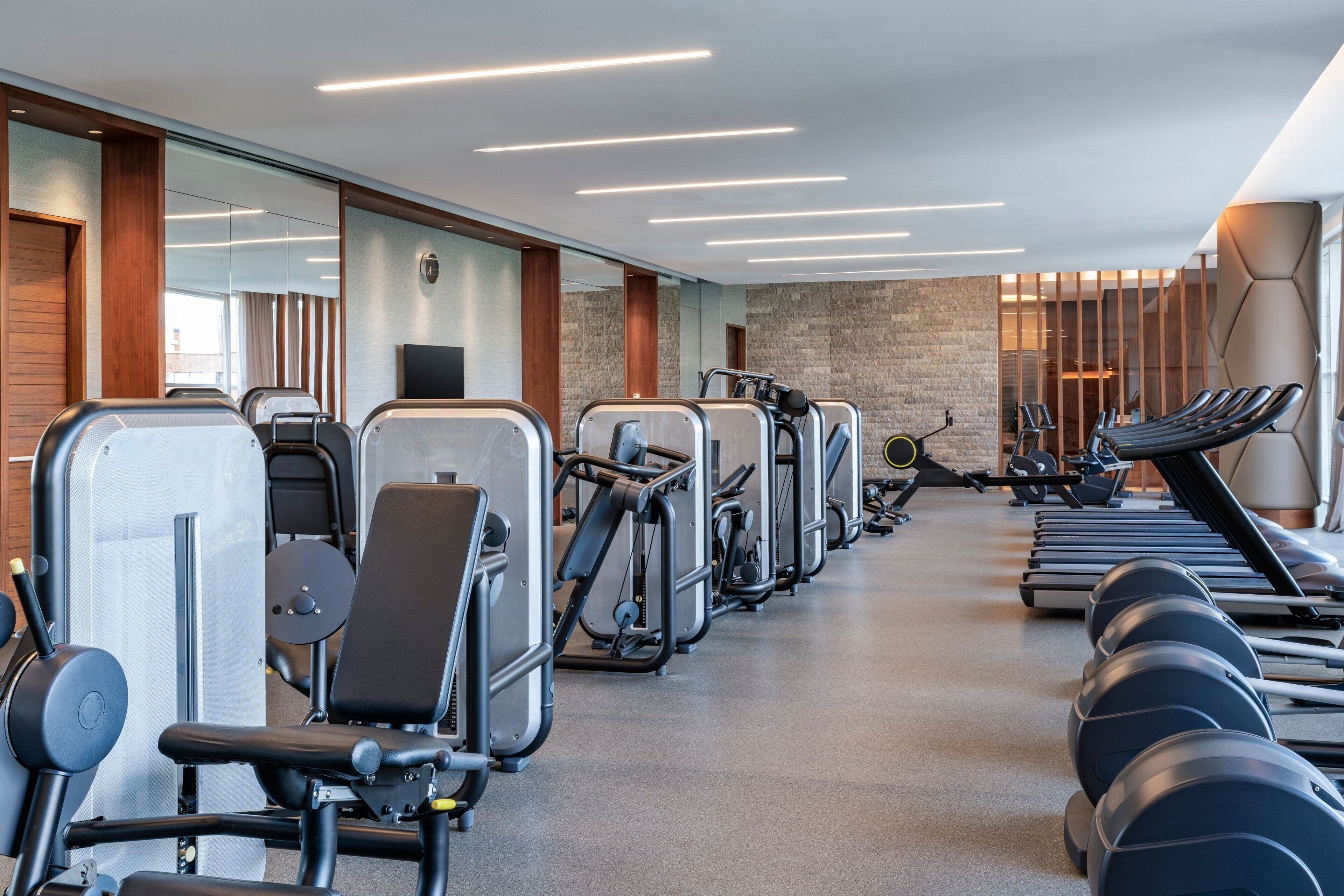Un gimnasio con equipo de ejercicio, espejos y una pared con un diseño texturizado.